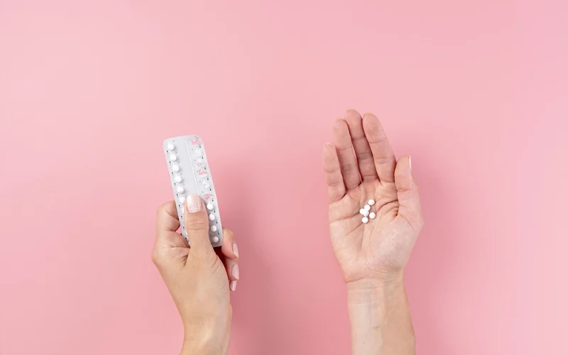 Woman holding birth control pills in her hand